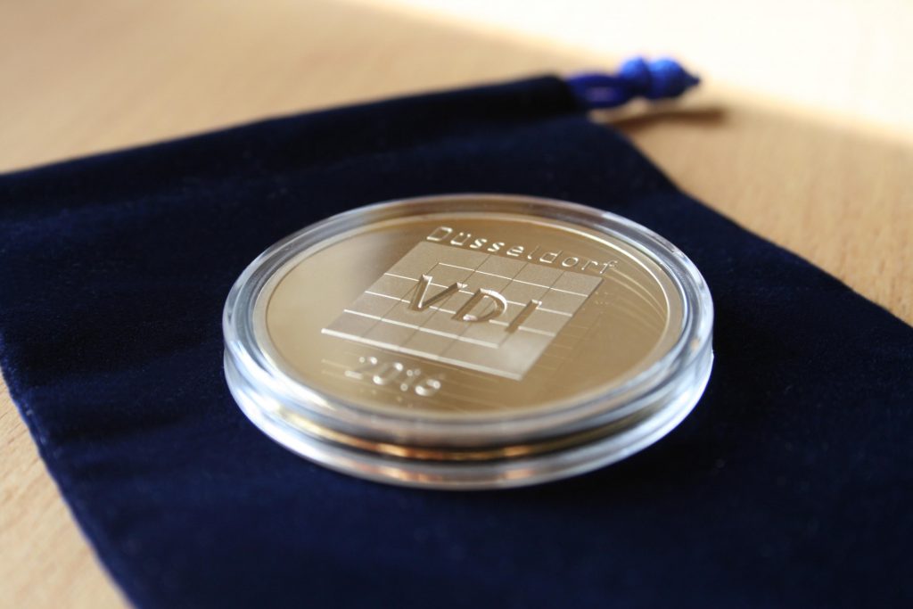 Individuelle Vereinsmünze vom VDI auf blauem Samtsäckchen ausgestellt